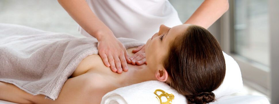 Eine Frau liegt mit dem Rücken auf einer Massageliege und bekommt eine Dekolleté Massage