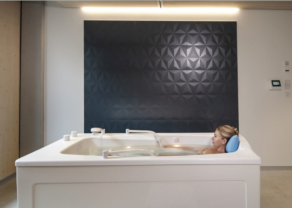 Eine Frau liegt entspannt in einer weißen Badewanne
