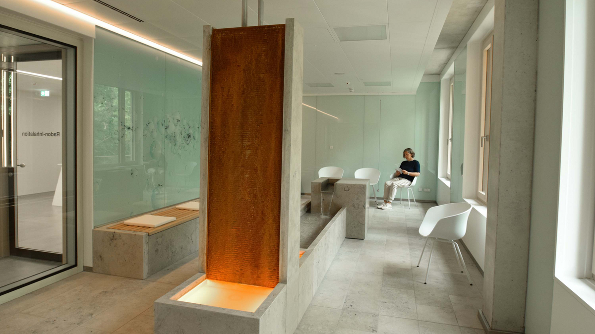 A woman sits in a corner on a chair in the inhalation room of the radon therapy center